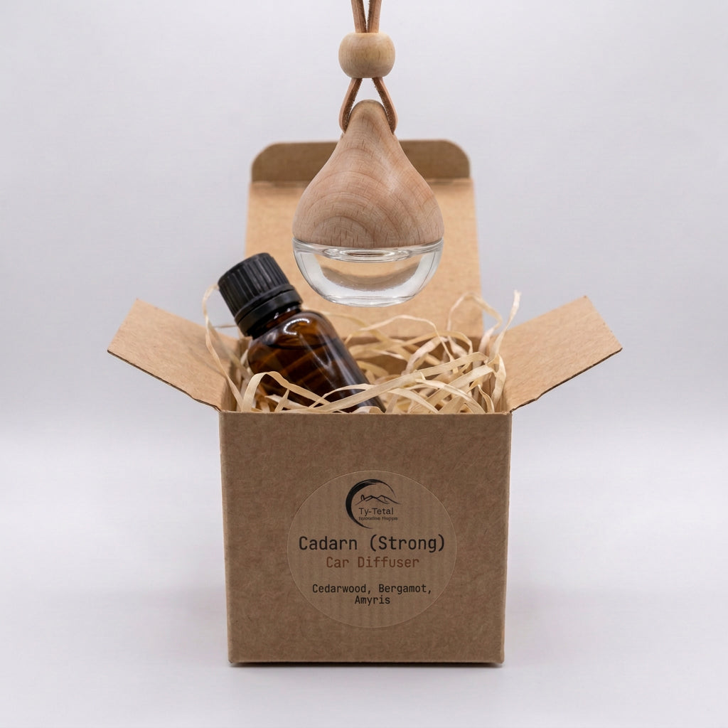 Cadarn (Strong) glass car diffuser with a wooden cap and amber refill bottle, displayed in a branded kraft box with shredded-paper filling.