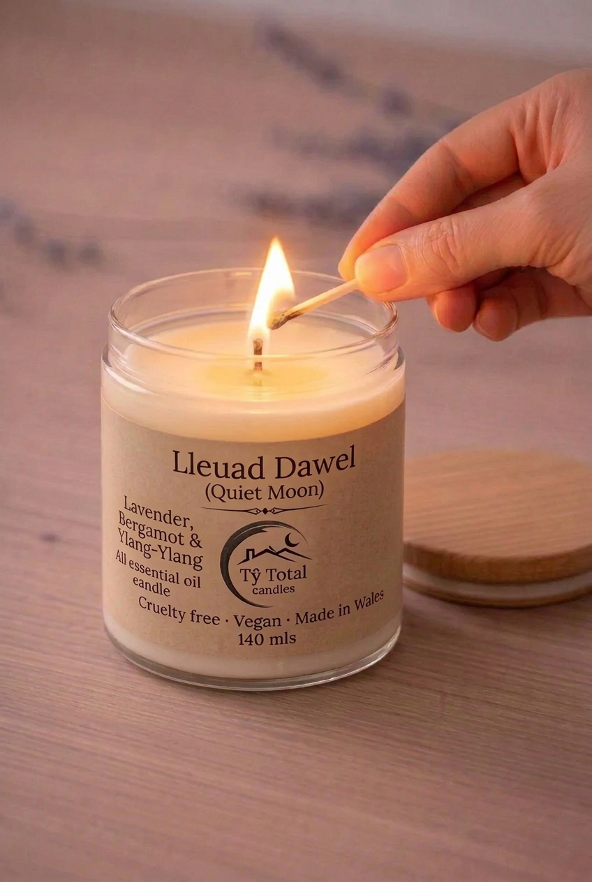 Lleuad Dawel (Quiet Moon) lavender, bergamot and ylang-ylang candle in a glass jar, being lit with a match.